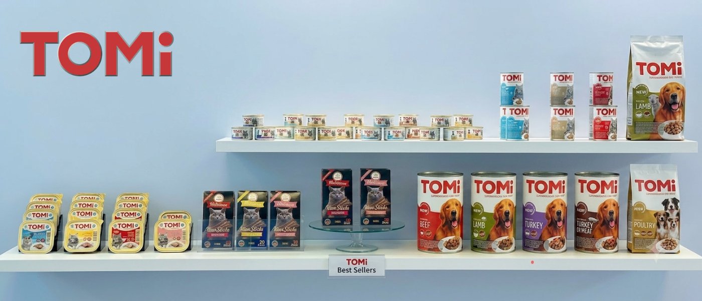 מגוון מוצרי טומי Tomi לכלבים וחתולים מונחים על המדף, פחיות שימורים, מגשיות מזון רטוב, חטיפים, שלוקים לחתולים ועוד