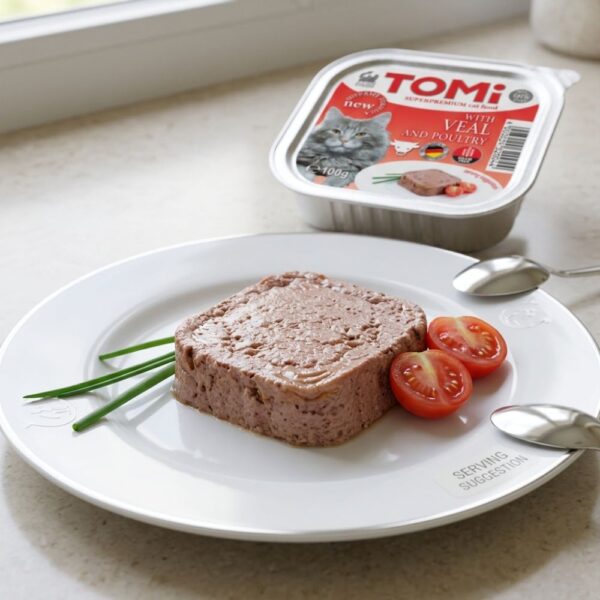 מעדן פטה לחתולים טומי (TOMi) בטעם עגל ועוף במגשית אלומיניום 100 גרם, מוגש על צלחת לבנה מעוצבת.